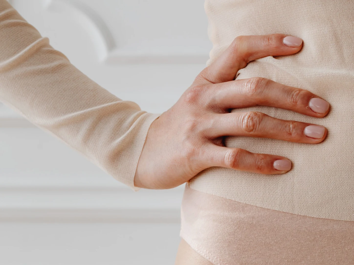 Eine Frau legt ihre Hand auf den Unterbauch